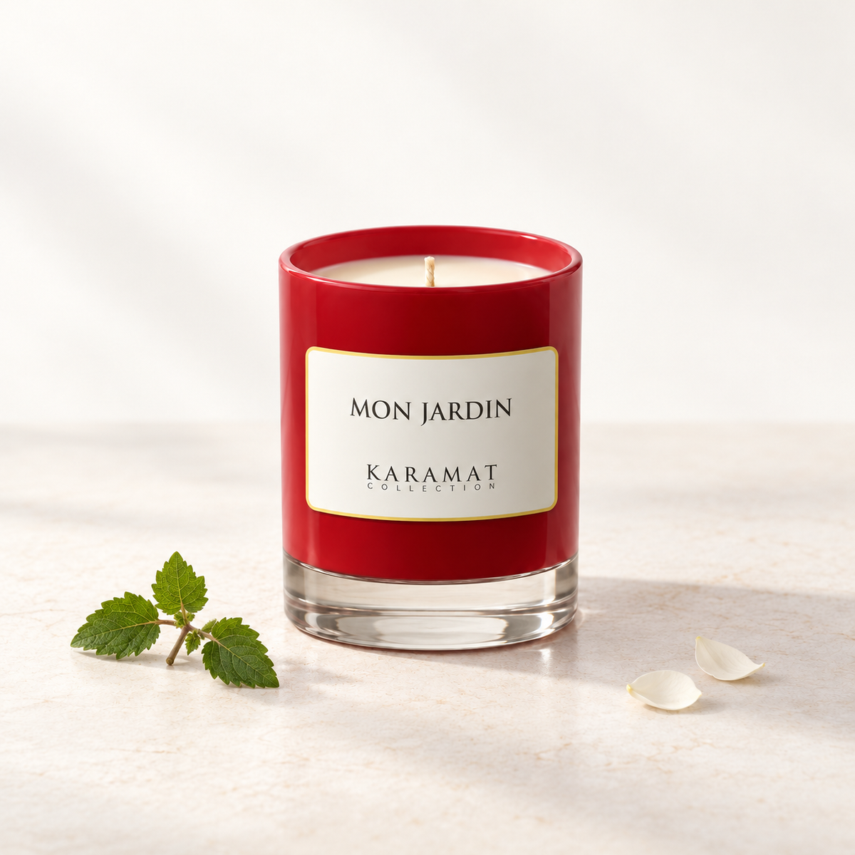 Bougie parfumée Mon Jardin, pot rouge avec une petite touche de feuillage et des pétales blancs.