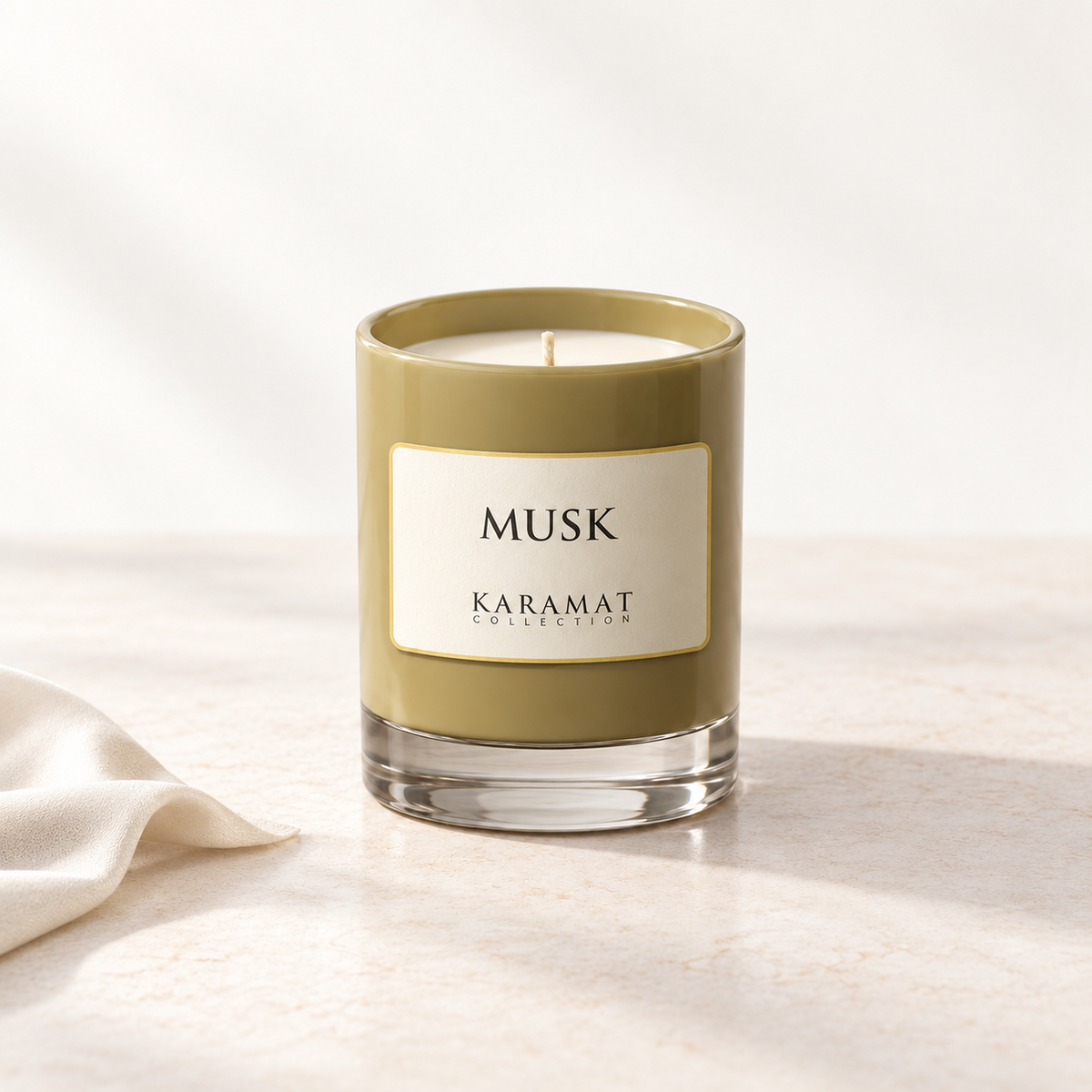 Bougie parfumée Musk, pot aux tons olive et tissu ivoire évoquant la douceur du musc.