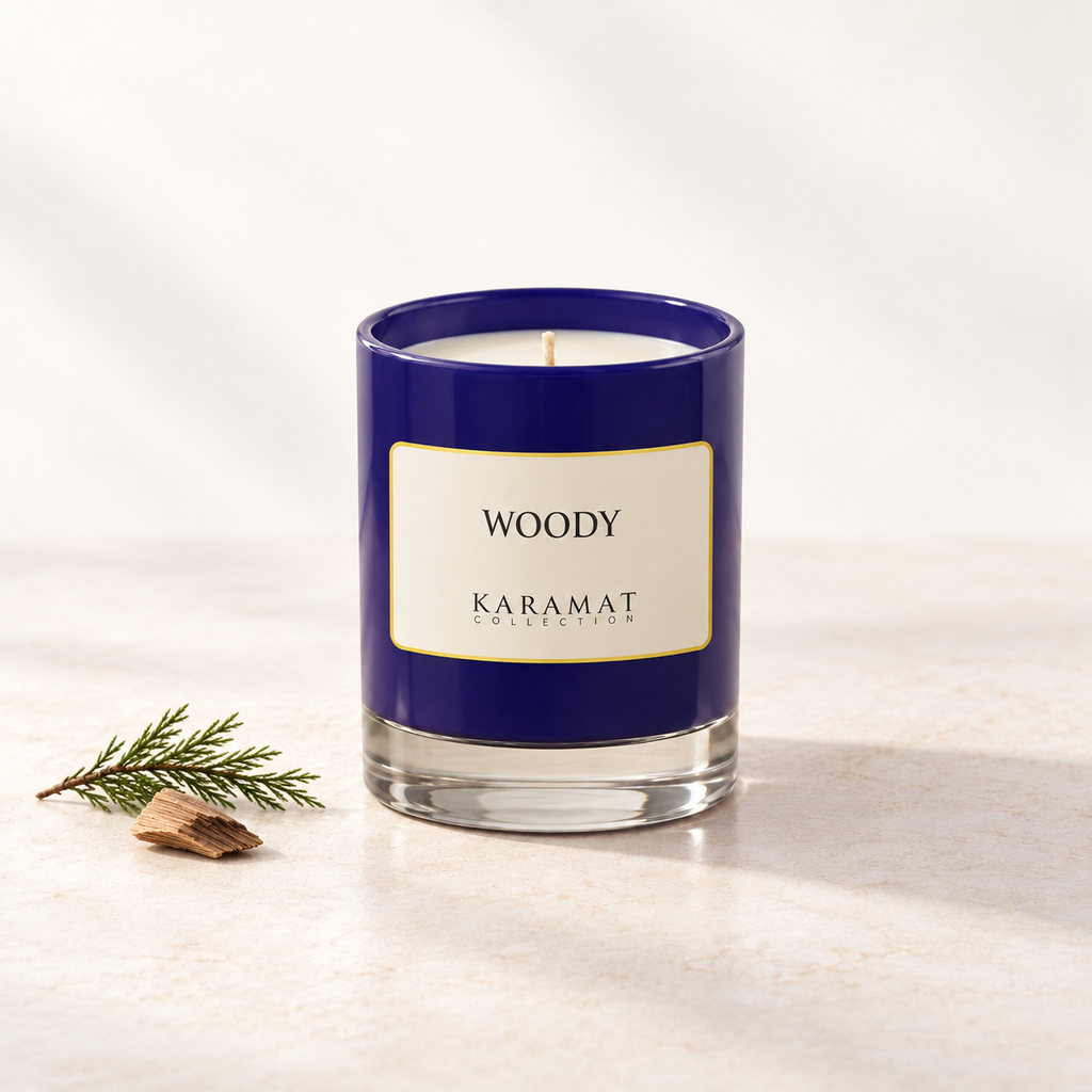 Bougie parfumée Woody, pot bleu et touches discrètes de bois et de feuillage pour évoquer ses notes boisées.