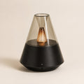 Brume, diffuseur d'ambiance Solveine noir avec dôme effet verre et lumière chaude effet flamme, vue de face sur fond beige