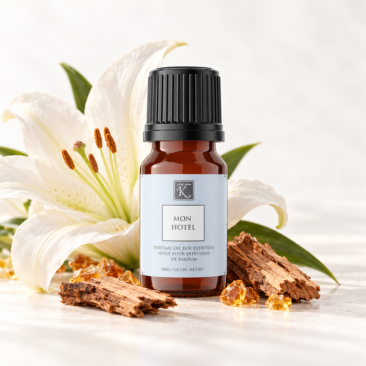 Huile parfumée Mon Hotel 30 ml, mise en scène avec un lys, du cèdre et de l’ambre pour évoquer sa senteur.