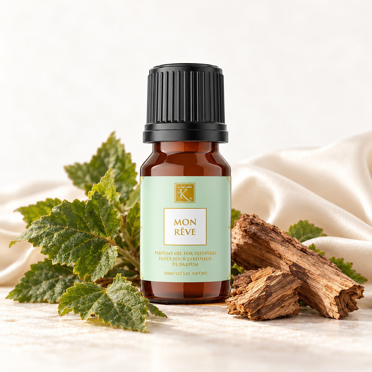 Huile parfumée Mon Rêve 30 ml, mise en scène avec du patchouli, du bois et un tissu clair pour évoquer ses notes.